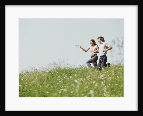 Young teen couple boy girl running field wildflowers by Anonymous