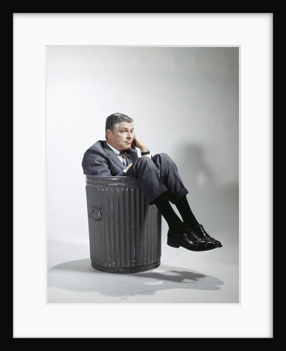 Sad man in business suit sitting in trash garbage can by Anonymous