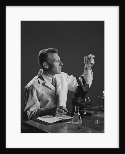 Man scientist holding test tube making notes by microscope by Anonymous
