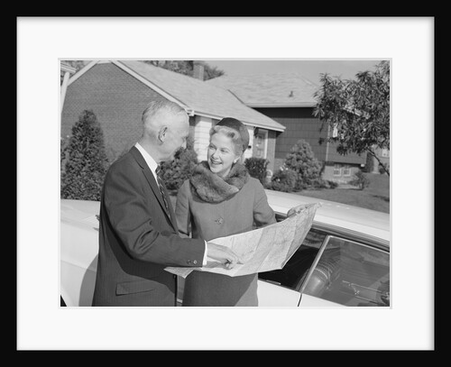 Senior man and woman by car looking at map by Anonymous