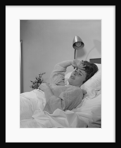 Ailing woman patient lying in hospital bed hand pressed to forehead by Anonymous