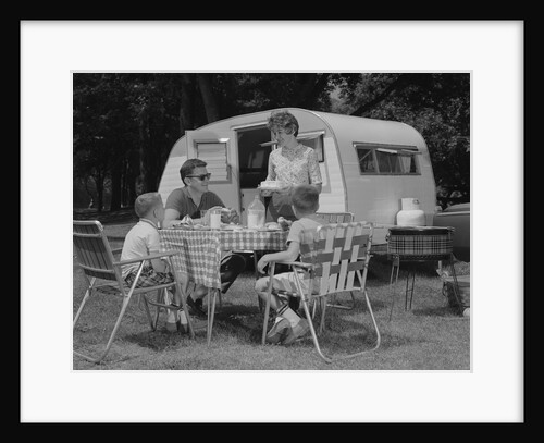 Family camping eating meal beside rv camper by Anonymous