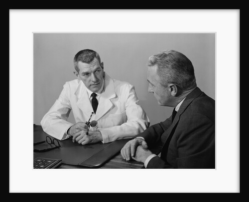 Doctor sitting at desk talking to male patient by Anonymous