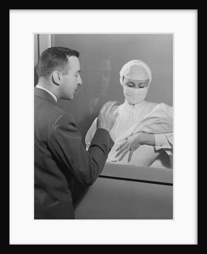 Female nurse holding infant up to father at nursery window by Anonymous