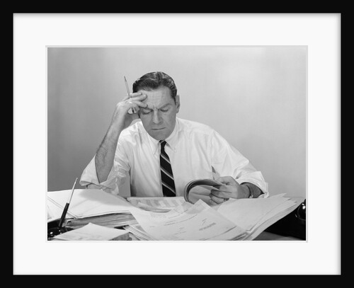 Businessman desk full papers hand to forehead serious expression by Anonymous