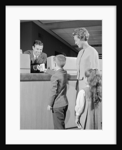 Mother two children boy handing banking deposit to male bank teller by Anonymous