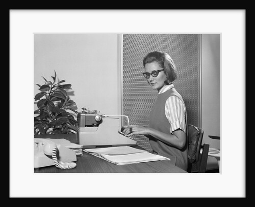 Secretary typist wearing stylish eyeglasses using manual typewriter at desk by Anonymous