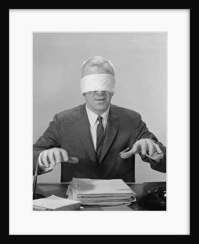 Business man hands hovering over desk wearing blindfold by Anonymous