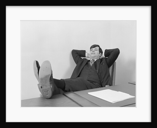 Confident young businessman sitting relaxed with feet up on desk by Anonymous