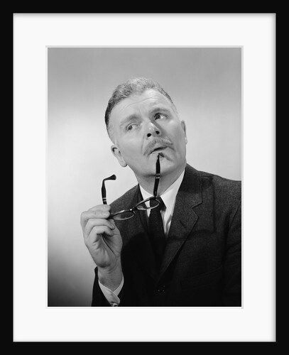Serious thinking thoughtful older man holding eyeglasses to chin by Anonymous