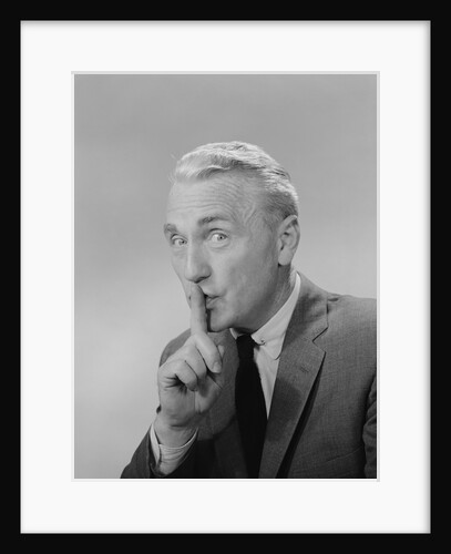 Middle aged man finger to lips making quiet shush sign by Anonymous