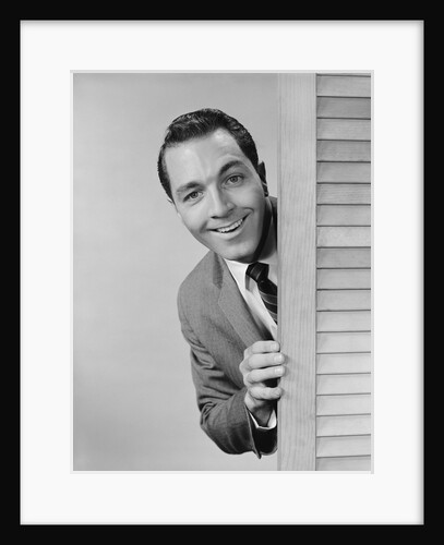 Smiling man business suit peeking from behind louvered door by Anonymous