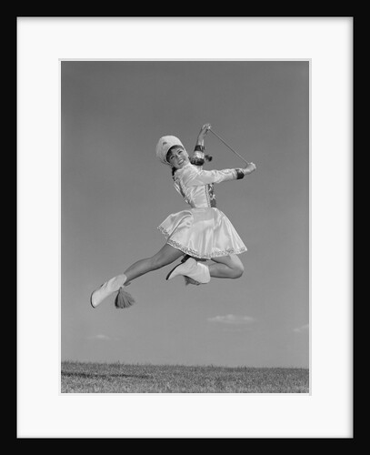Woman majorette wearing band uniform holding baton jumping into the air by Anonymous