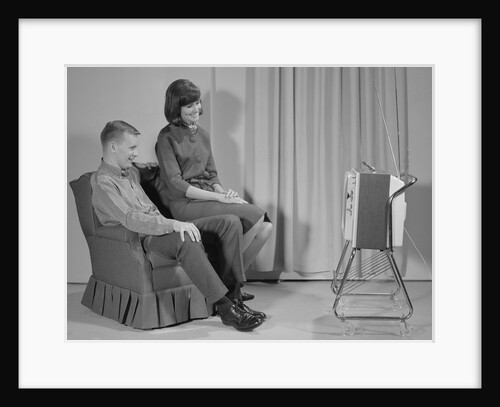 Couple man woman sitting chair watching portable television by Anonymous