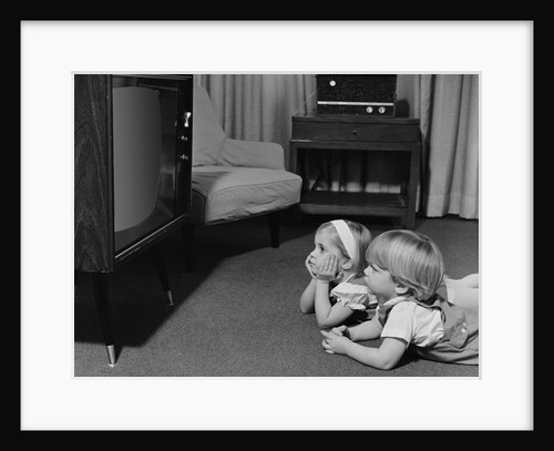 Two toddlers boy girl lying on floor watching television by Anonymous