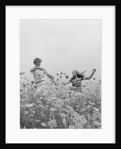 Young couple holding hands running through field of flowers by Anonymous