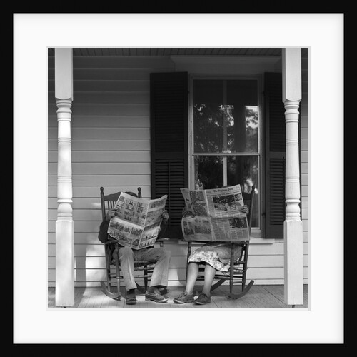 Couple man woman sitting on porch in rocking chairs holding newspapers up hiding their faces by Anonymous