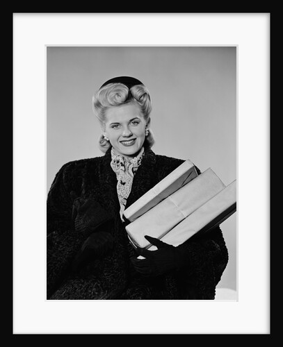 Blond woman smiling wearing winter coat carrying shopping parcel by Anonymous