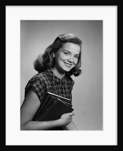 Young smiling woman holding books looking at camera by Anonymous