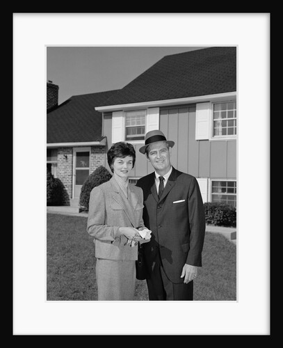 Couple smiling man and woman standing before suburban house by Anonymous