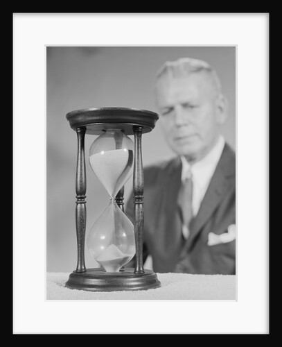 Elderly man soft focus behind hourglass by Anonymous