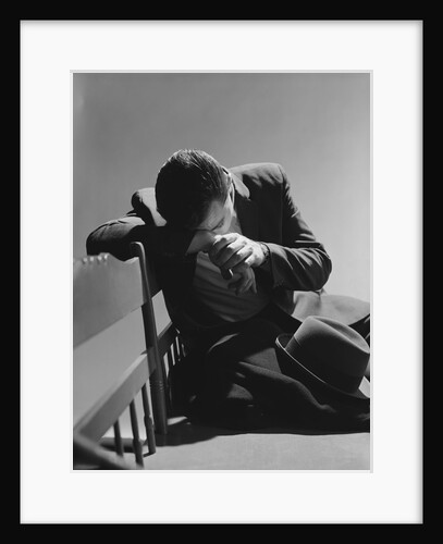 Businessman sitting on bench head down on arms slumped over sad depressed by Anonymous