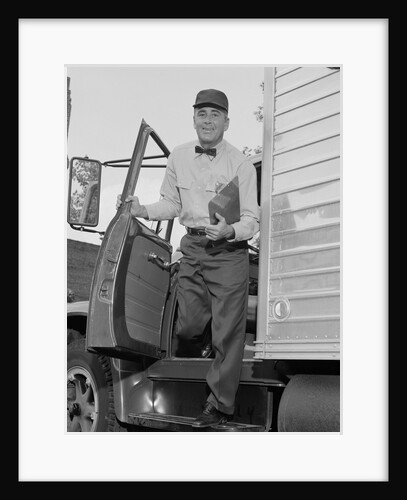 Delivery man stepping out of truck holding clipboard by Anonymous