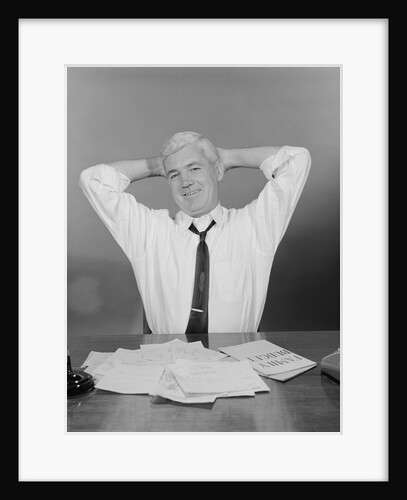 Smiling man working on family budget papers at desk by Anonymous