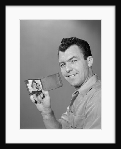 Smiling man holding up wallet with picture of wife and daughter by Anonymous