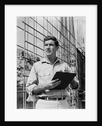 Man on construction site holding clipboard by Anonymous