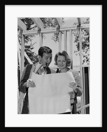 Couple looking at house plans blueprints man smoking pipe by Anonymous