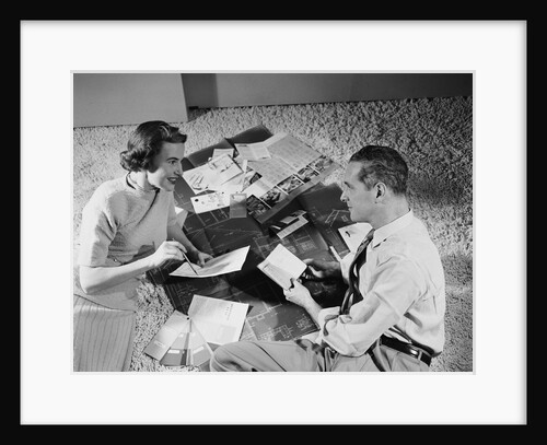 Couple man woman sitting floor looking at plans for new house by Anonymous