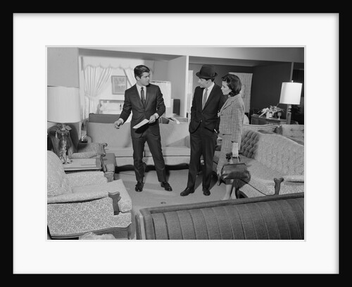 Furniture store salesman talking to couple by Anonymous