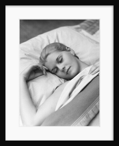 Sleeping blond woman eyes closed head resting on pillow in bed by Anonymous