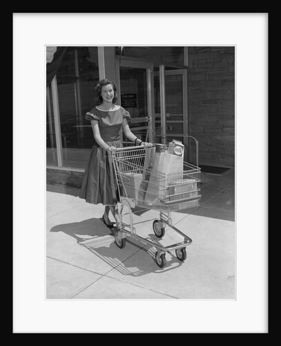 Smiling woman pushing grocery cart out of supermarket by Anonymous