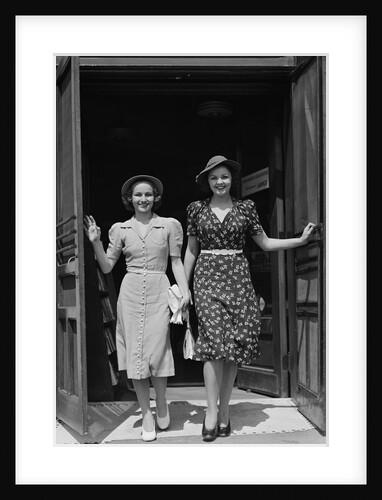 Two smiling women walking out doorway of a store by Anonymous