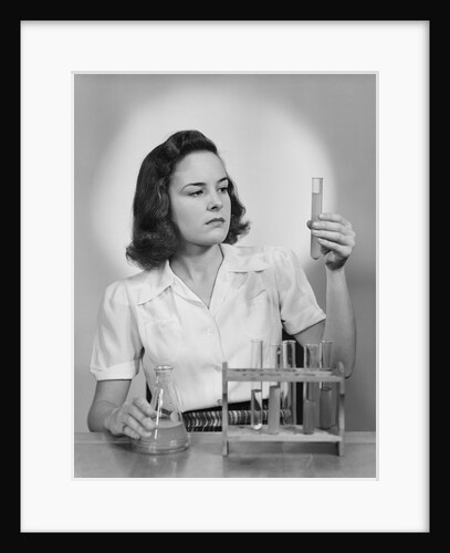 Young woman chemist holding up test tube by Anonymous