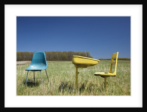 Abandoned school desk anc chairs in field by Anonymous