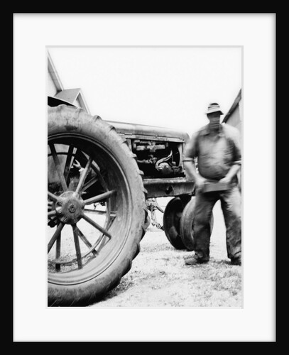 Farmer is a blur of activity working on his tractor, ca. 1938 by Anonymous