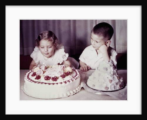 Brother watches his sister blow out candles on birthday cake, ca. 1956 by Anonymous