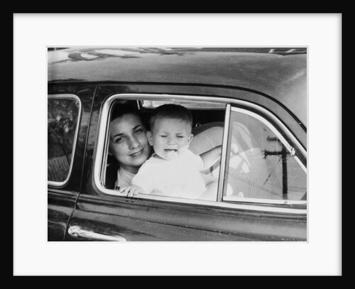 Mother holds crying son in her lap in car, ca. 1954 by Anonymous
