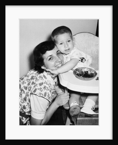 Baby boy hugging mother at dinner time, ca. 1953 by Anonymous