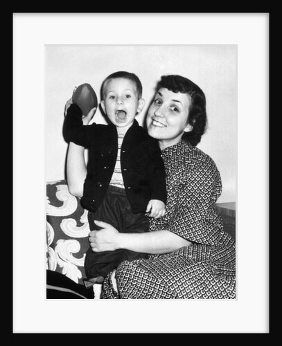 Little boy holding football with his mother, ca. 1955 by Anonymous