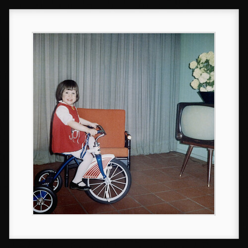 Young girl rides her new tricycle in the house, ca. 1967 by Anonymous