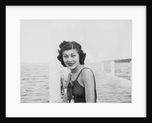 Young woman smiles and sits on a swimming pier, ca. 1938. by Anonymous
