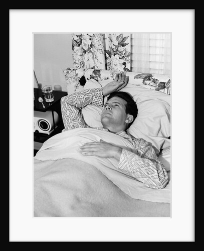 1940s 1950s sick man in bed in pajamas one hand on chest one above his head on pillow by Anonymous