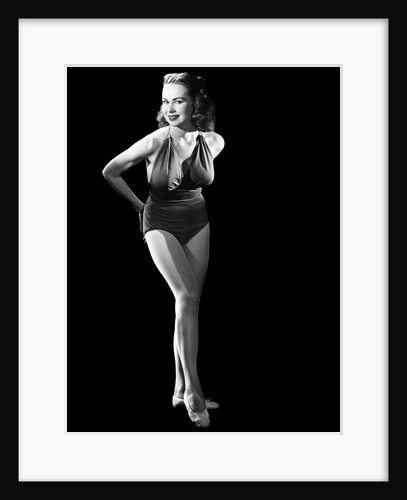 1950s busty young woman posing standing inside wearing bathing suit looking at camera by Anonymous