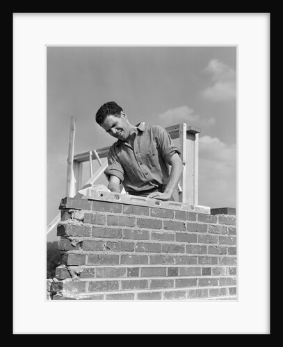 1940s man working with level on brick wall chimney construction by Anonymous