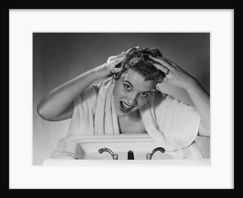1950s smiling woman washing shampooing hair in sink looking at camera by Anonymous