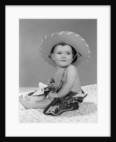 1960s baby girl wearing cowboy hat toy holster and guns indoor by Anonymous